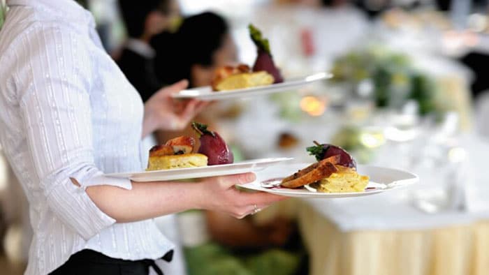 A waitress carries three plates at a restaurant.