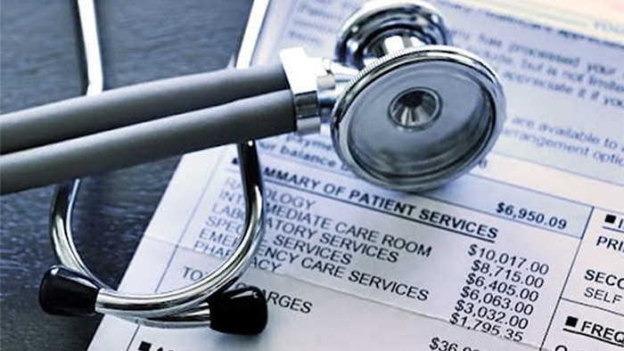 A stethoscope lies on top of a medical bill.