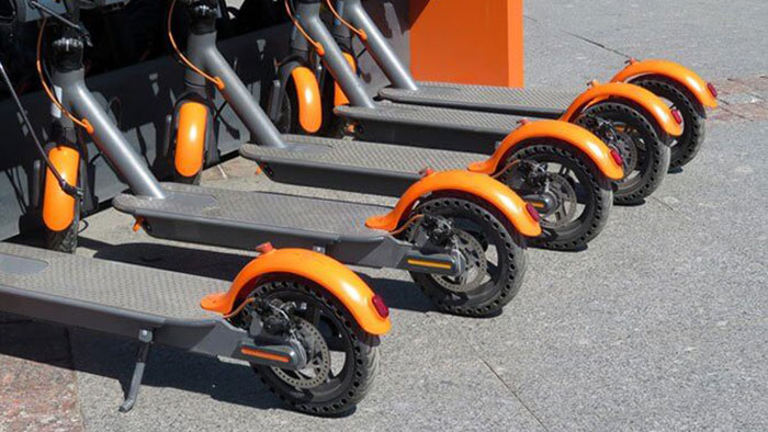 A row of 5 electric scooters.