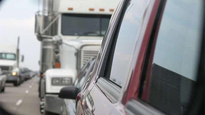 An rear-view image from a vehicle with a tractor-trailer behind them.