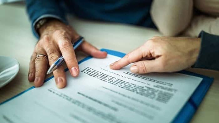 The focus is on a lawyer showing a client where to sign a document.