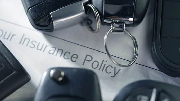 A bunch of car keys over a document that says, "your insurance policy. "