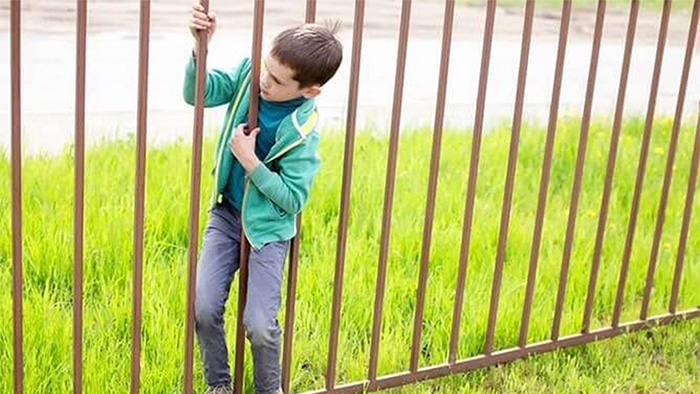 kid sneaking through a fence