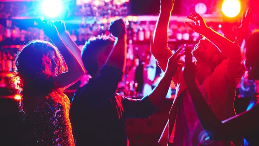 Four individuals dance at a bar