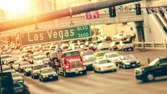 Up close shot of the S Las Vegas Blvd road sign. In the background, traffic backs up at the red light.