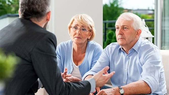 The back of a lawyer talking to his two clients.