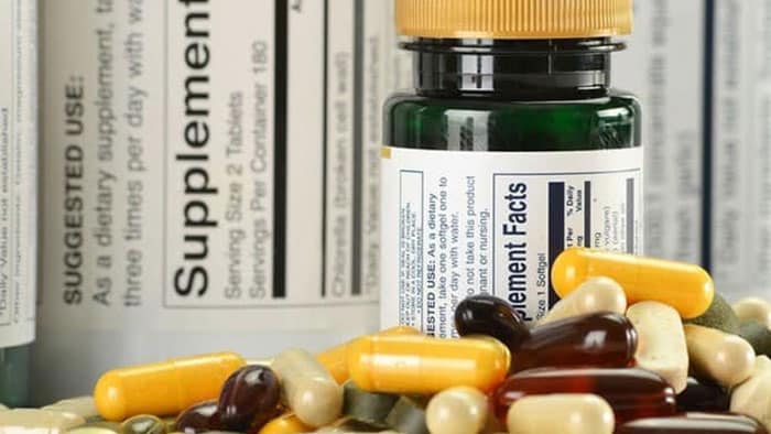 An up-close view of dietary supplements piled in front of a bottle.