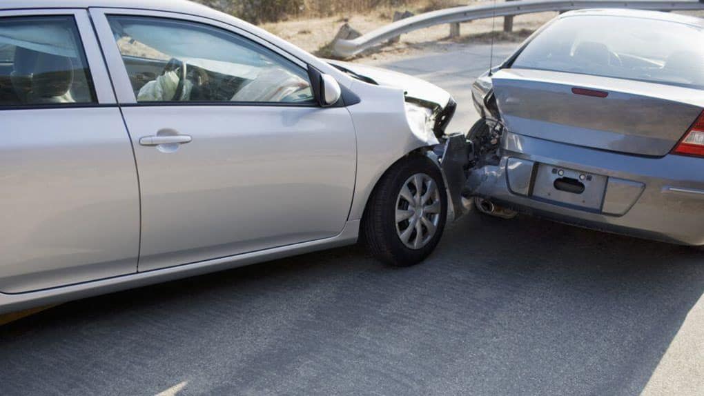 An up-close image of a fender bender. Both vehicles have damage to their bumper.