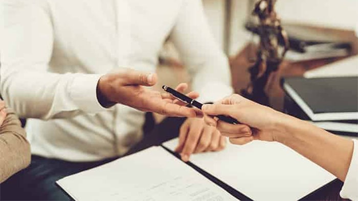 Personal injury lawyer handing a pen to a client