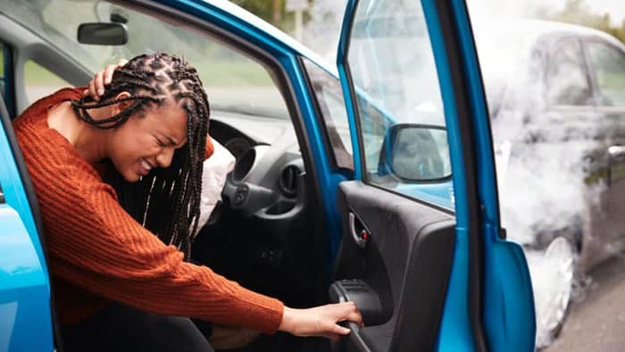 A woman is holding her neck in pain as she exits her vehicle.