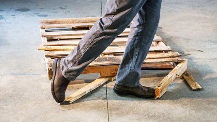 A close-up view of someone tripping over a broken wooden pallet.
