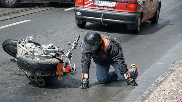 A man is on his hands and knees after falling off a motorcycle after an accident.