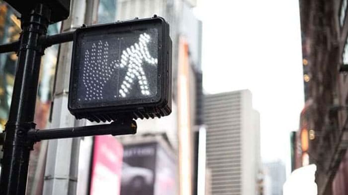 An up-close shot of the walking man light at a crosswalk.