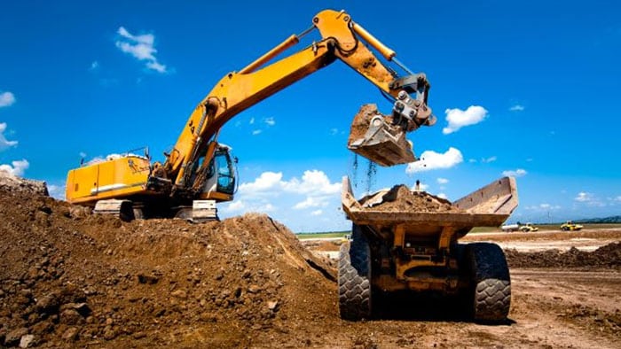 tractor trailer loading dirt into a dump truck