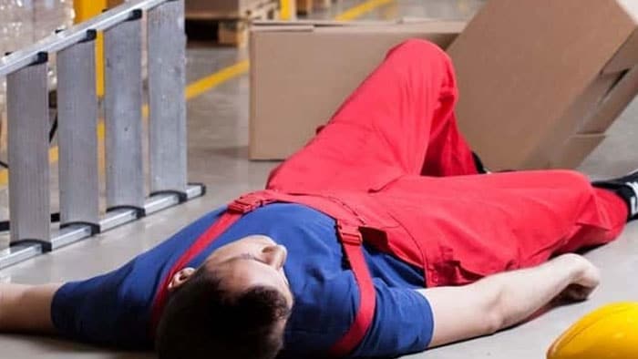 An injured man lies unconscious on the floor next to a fallen ladder.