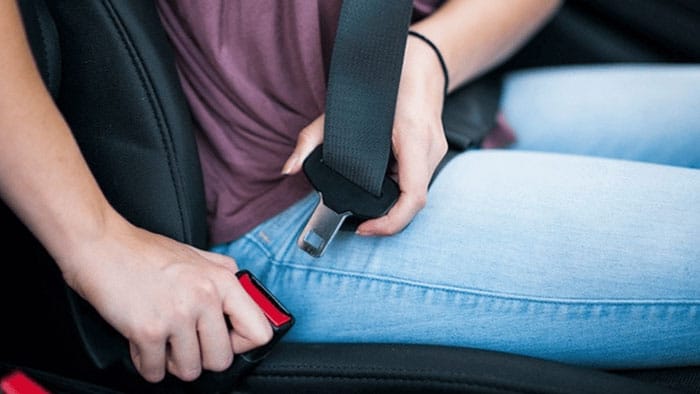 person buckling a seat belt