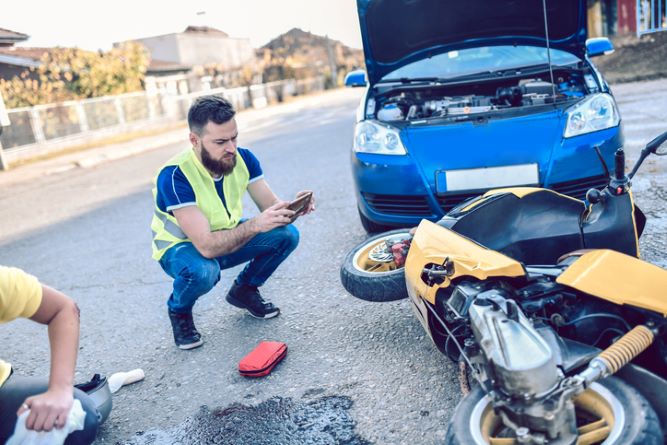 man-taking-a-photo-of-a-traffic-accident-involving-a-car-and-motorcycle