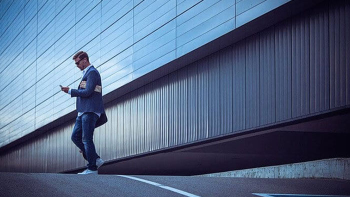 A man is walking while distracted by his phone.