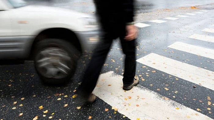 The focus is on a car almost hitting a person using the crosswalk.