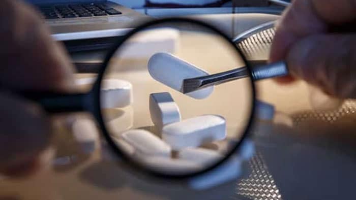 An up-close view of a magnifying glass inspecting medication.