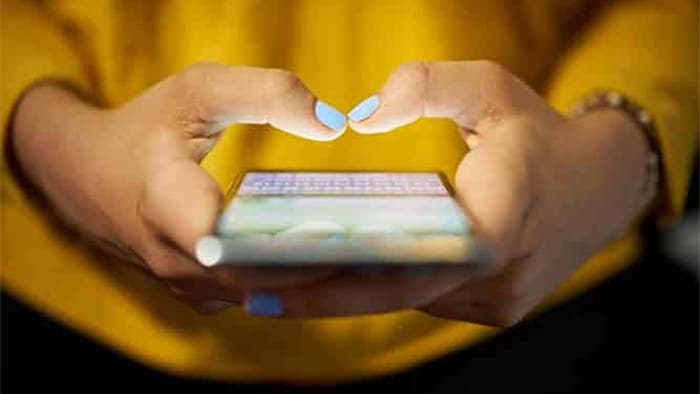 The focus is on someone's hands as they hold their smartphone.