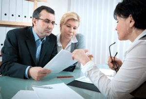 A lawyer is showing paperwork to her two clients.