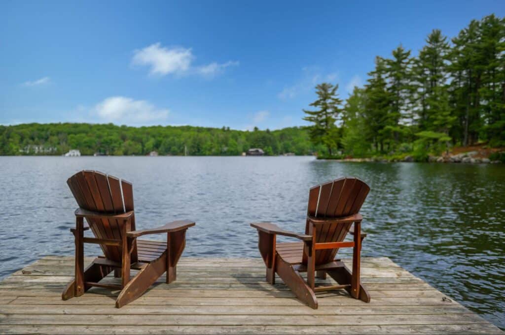 two wood chairs looking over a lake at an airbnb
