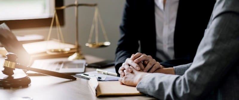 injury lawyer and client at desk holding hands