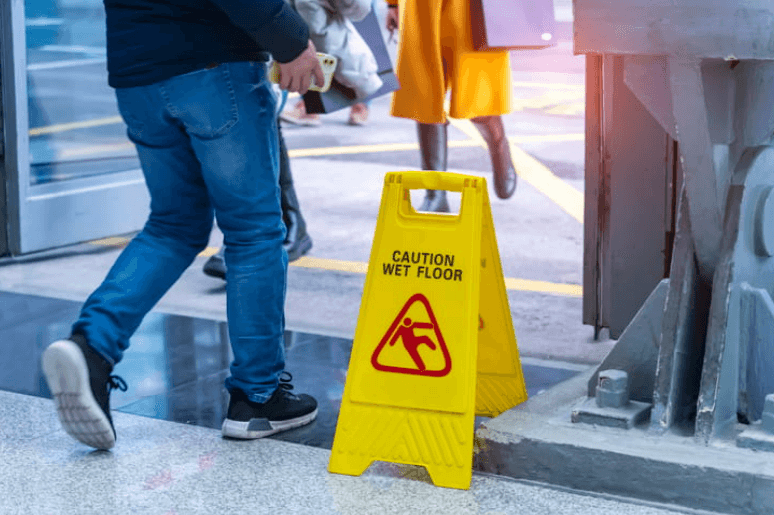A person walking by a caution: wet floor sign