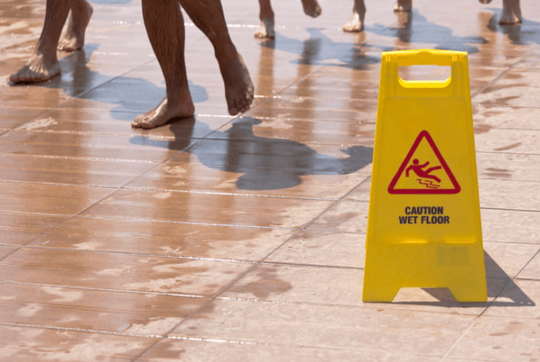 A caution: wet floor sign outside a swimming pool