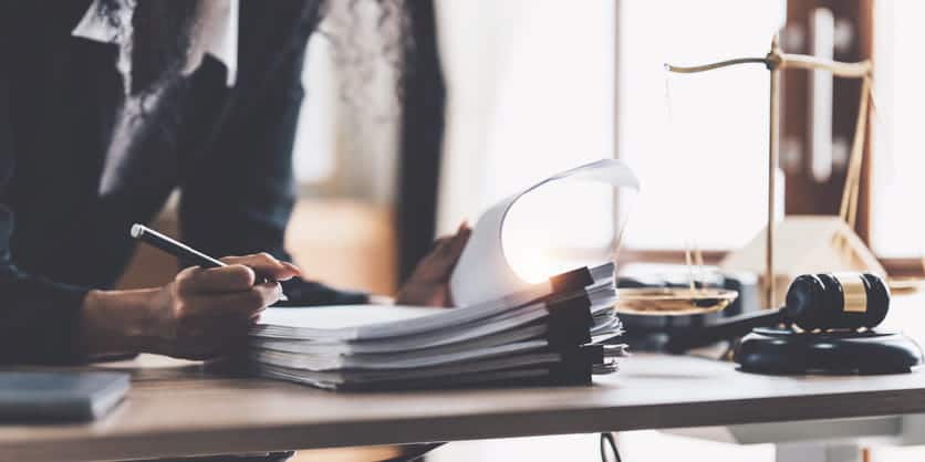 Focus is on an unidentifiable lawyer working on paperwork at her desk.