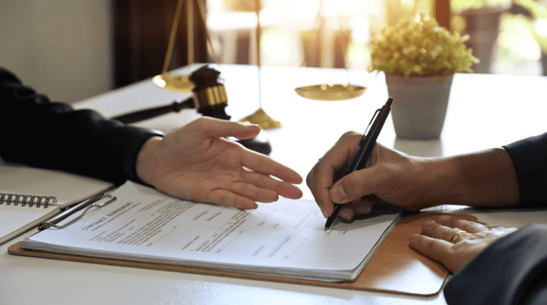 Personal Injury Claim Disputes 1 Focus is on a lawyers hand filing out paperwork for a client regarding a person injury claim.