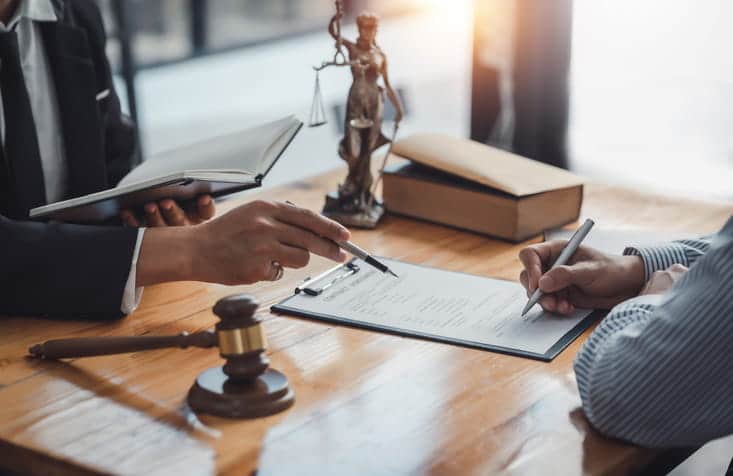 Focus is on a lawyer showing paperwork to their client.