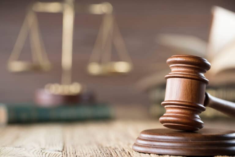Faking Injury In Car Accidents 2 A closeup of a gavel on a car accident attorney 's desk in las vegas. In the background is a blurred-out view of the scales of justice sitting atop a book.
