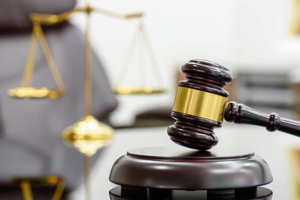 A closeup of a gavel on a worker's comp lawyers desk with a blurred out scales of justice in the background.