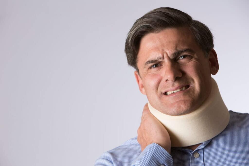 A man wearing a neck brace, faking an injury after a car accident.