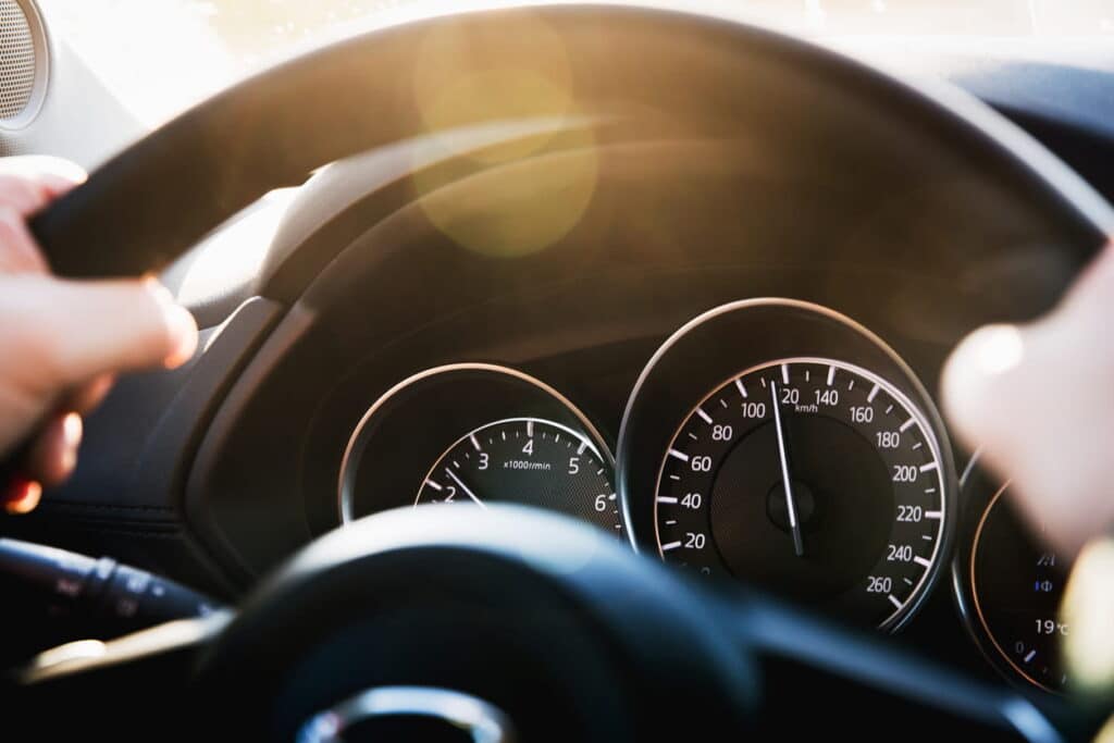 Focus is on a car's speedometer showing that a car is speeding.