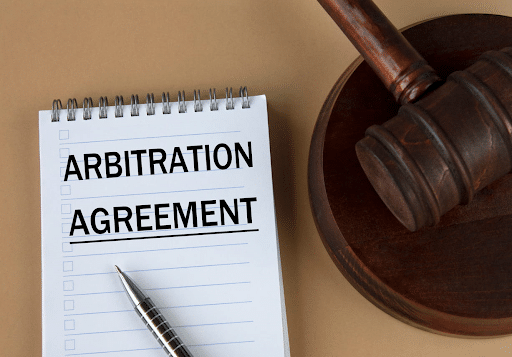 A notepad that reads: "arbitration agreement" next to a gavel.