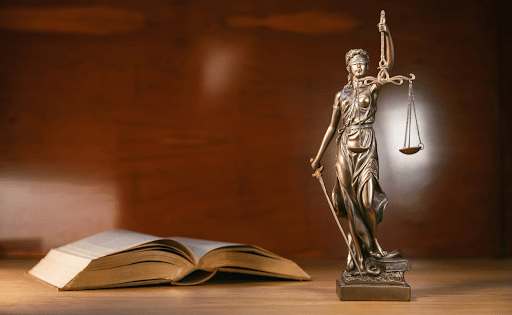 A Lady Justice statue next to an open book on a personal injury attorney's desk.