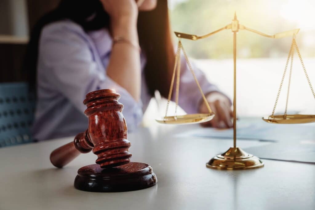 A car accident lawyer sitting at her desk. On her desk is the scales of justice and a gavel.