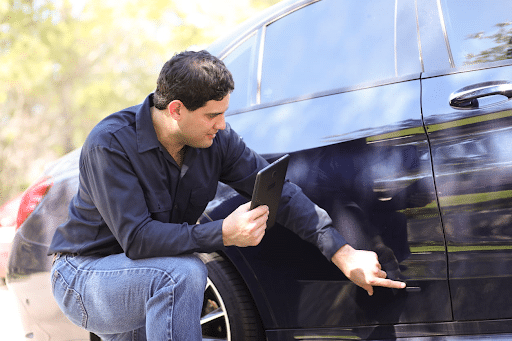 A man pointing out property damage on his vehicle.