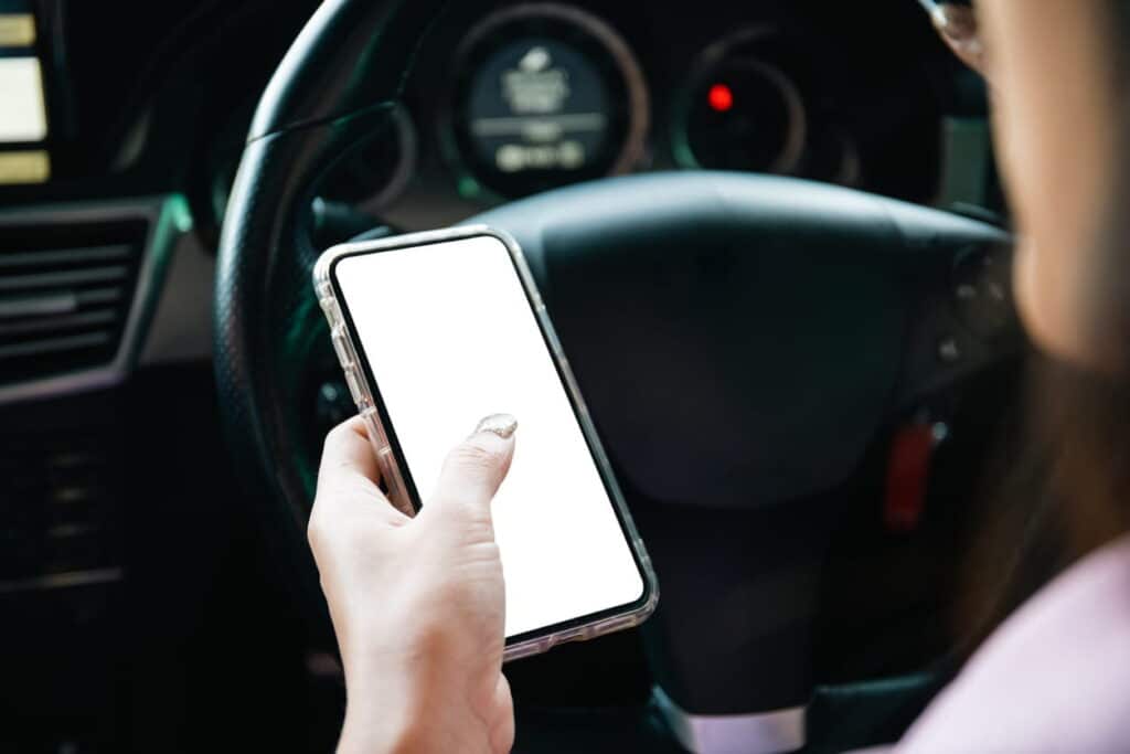 A person on their cellphone behind the wheel as an example of reckless driving.