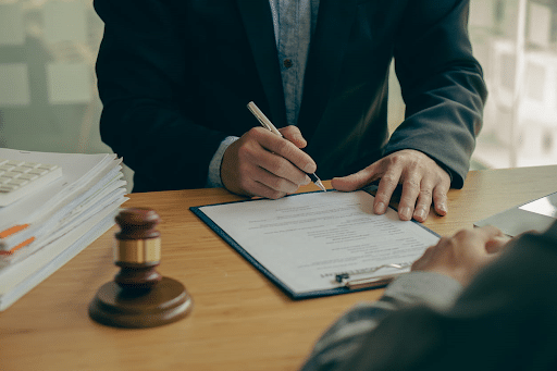 A personal injury attorney fills out paperwork on his desk. Next to him is a gavel.