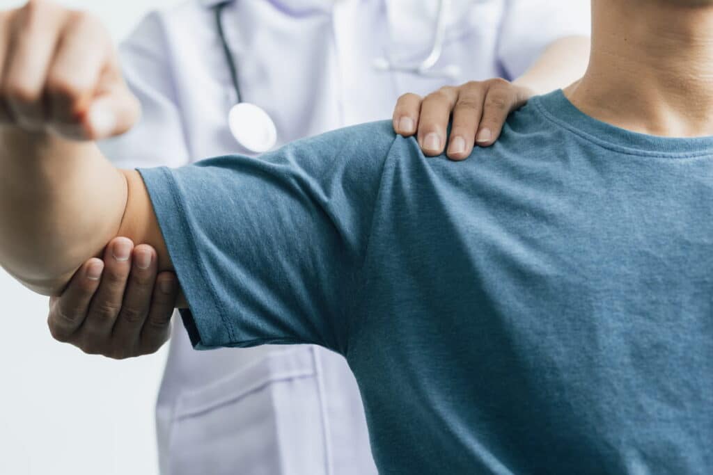 A doctor examining a patient's shoulder and arm after a personal injury.