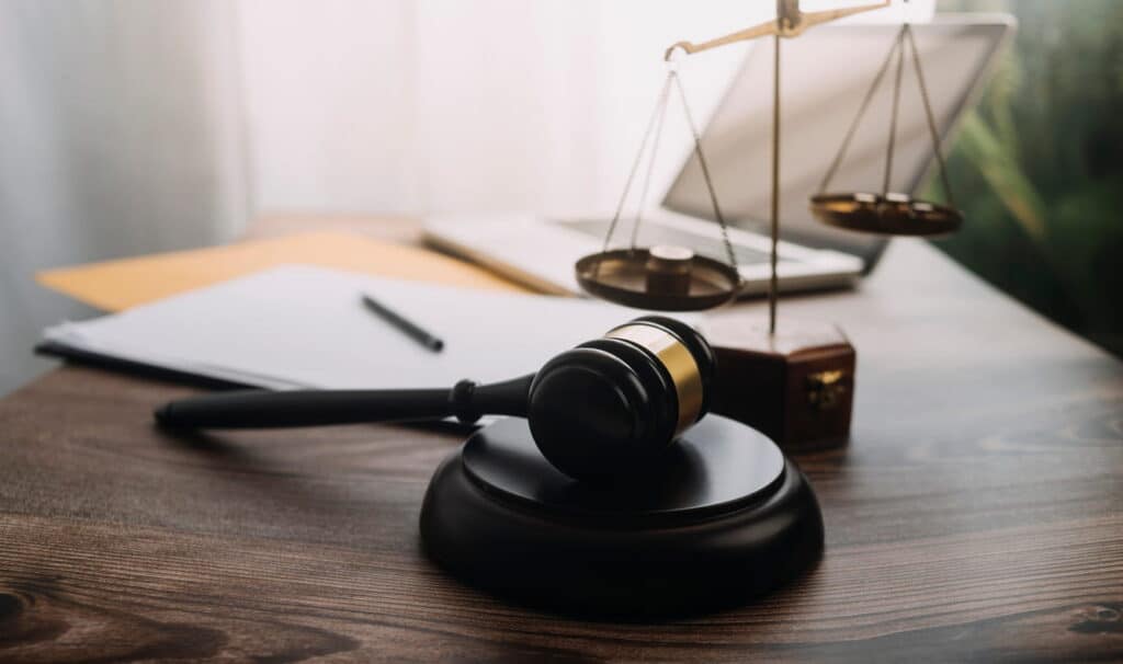 A gavel, paperwork, an open laptop, and the scales of justice on a Henderson attorney's desk.