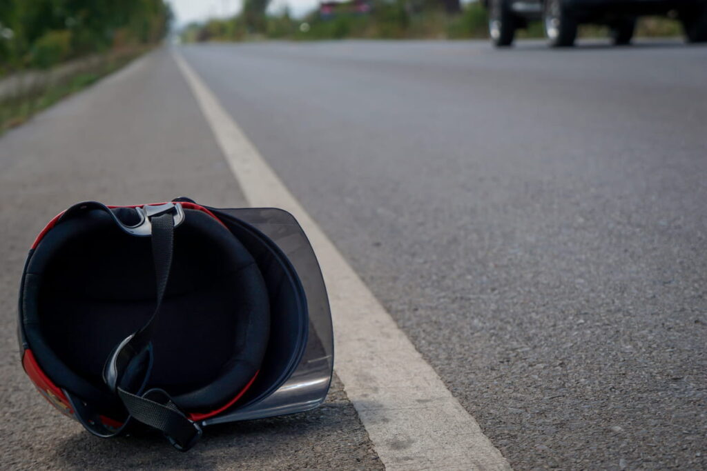 A helmet lying on the roadway after a motorcycle accident.