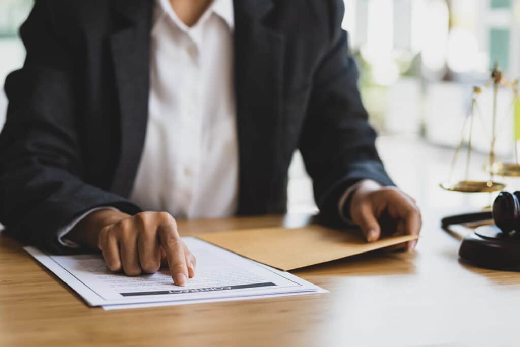 A personal injury lawyer reviewing paperwork at their desk. Next to them is a gavel and the scales of justice.