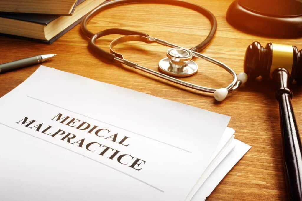 Papers that read: "Medical Malpractice." Next to them is a gavel and a stethoscope.