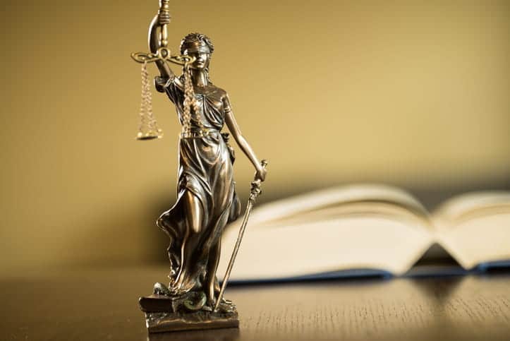 A Lady Justice statue on a casino injury attorney's desk in front of an open book. 
