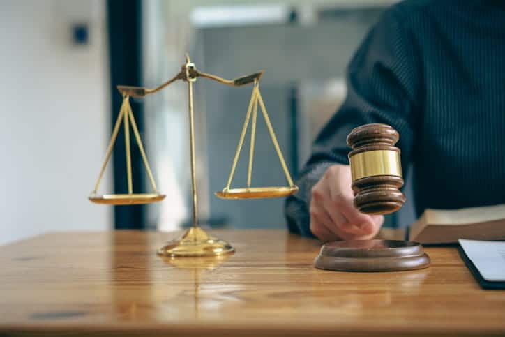 Should I Hire A Lawyer For A Minor Car Accident? 2 A car accident attorney using a gavel at his desk. Next to him is the scales of justice.
